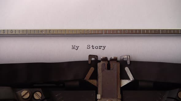 Typing phrase My Story on retro typewriter. Close up.