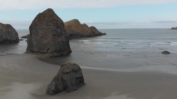 Still aerial of waves lapping the dark sandy beach of Oregon of Pacific Coast Highway 1, USA