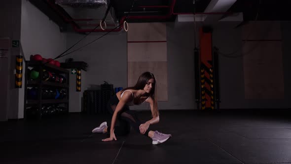 Young Energetic Girl Does Exercise Stretching for Leg Muscles in the Gym