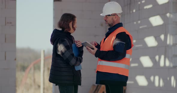 Concentrated Engineers Discussing Examining and Developing at Construction Site