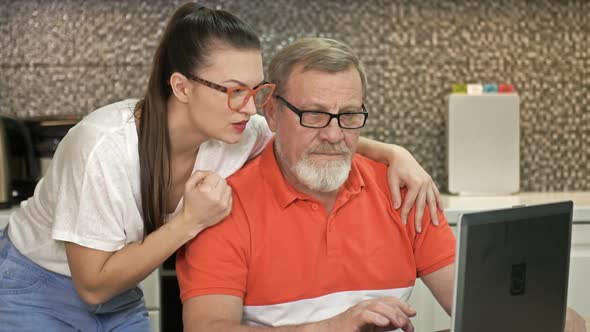 Adorable Brunette and Her Father Stare Intently at the Laptop Screen