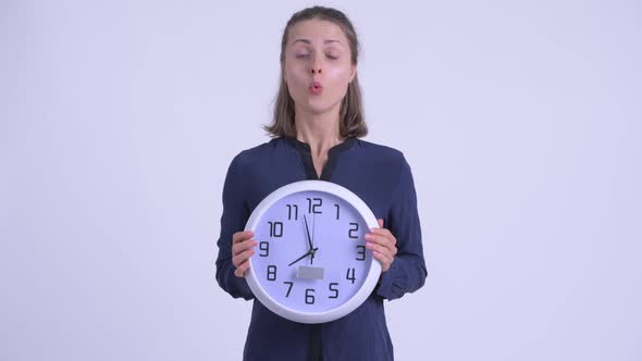 Young Businesswoman Holding Wall Clock and Looking Shocked