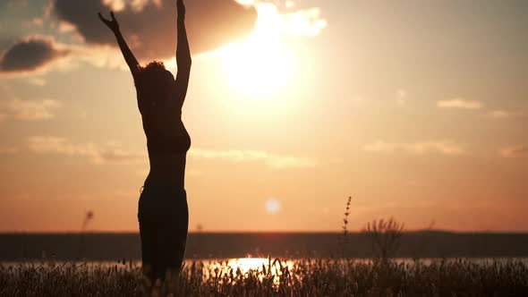 Silhouette of Young Beautiful Girl Practicing Yoga at Sunset