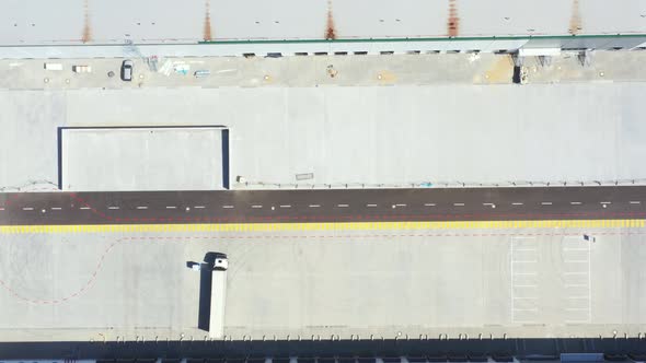 Aerial Shot of Industrial Warehouse Loading Dock where Many Truck with Semi Trailers Load Merchandis