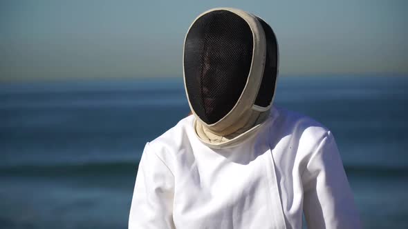 A man and woman fencing on the beach.