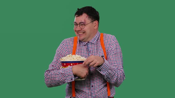 A Man Watches a Funny Movie Laughs and Eats Popcorn From a Large Bucket