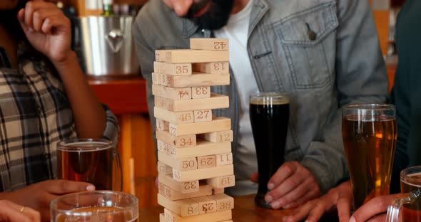 Group of fiends playing jenga while having beer 4k