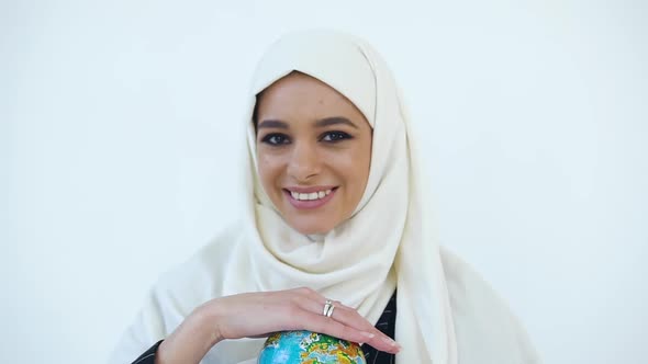 Muslim Woman in Hijab Holding in Her Hands Small Globe and Looking at Camera