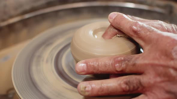 Professional Potter Turns Wet Clay on Potter's Wheel and Makes Hole in It with His Finger Macro