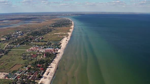 Beautiful flight in summer over the beach. People are resting near the sea. Houses for tourists.