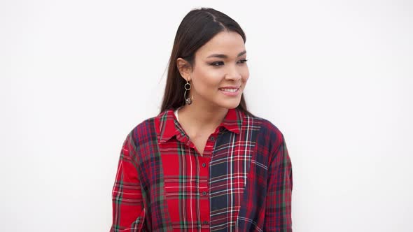 Young Woman in Trendy Outfit Standing Near White Wall and Looking at Camera