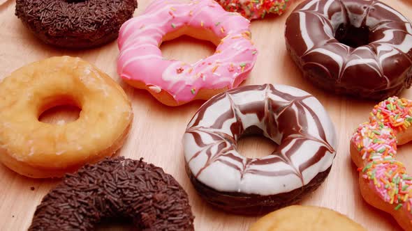 Various flavors of donuts on a rotating wooden plate.