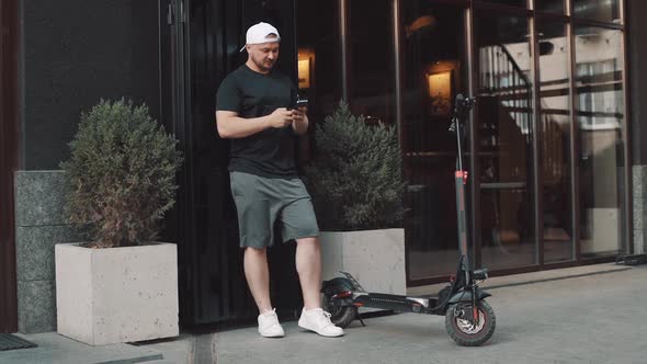 Tourist Man on Electric Scooter with Phone in Hand