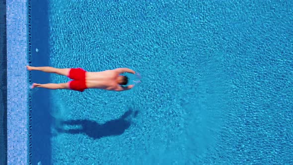 View From the Top As a Man Stands on the Edge of the Pool Dives and Swims Under the Water