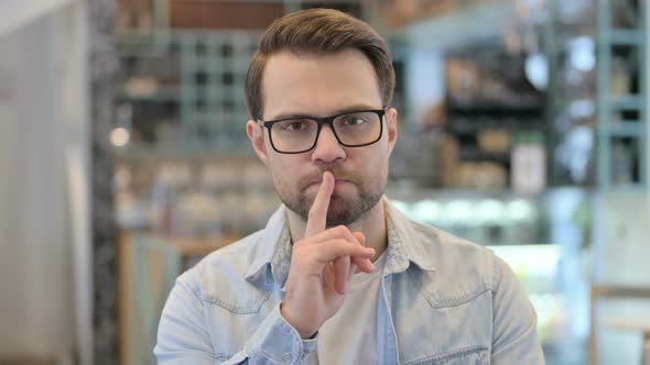 Young Man Putting Finger On Lips Quiet Sign