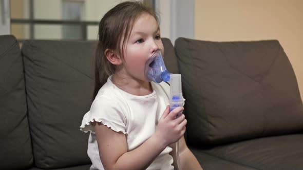 Little Girl Does Inhalation with a Mask on Her Face at Home