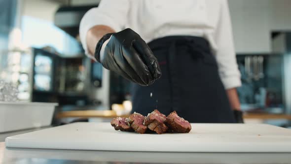 The chef sprinkles the filet mignon with coarse salt. Serving food in restaurant.