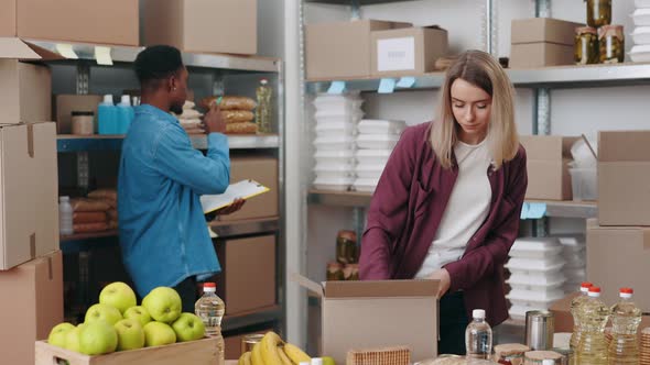 Woman Packing Food in Boxes While Man Writing on Clipboard