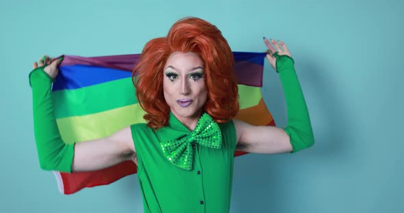 Happy drag queen holding rainbow flag while dancing inside the studio - Lgbtq concept