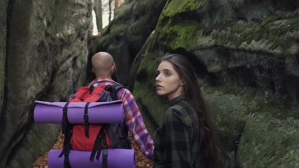 Man and Woman with a Backpack Walking Along the Path of a Pedestrian Path Between the Rocks