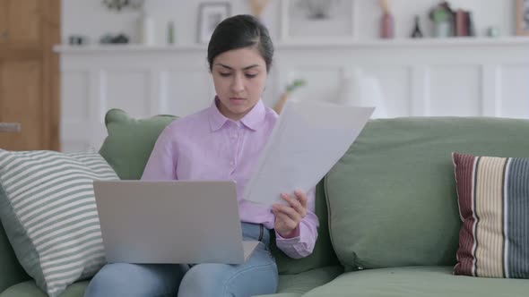 Indian Woman with Laptop Working on Documents on Sofa