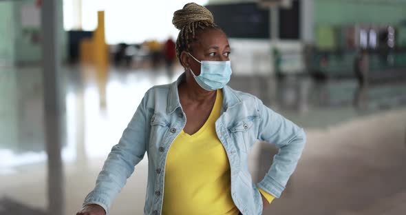 Mature african woman wearing safety face mask inside international airport