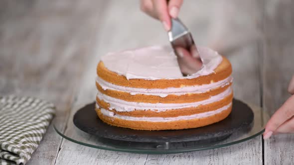 The process of decorating a cake with purple cream cover.