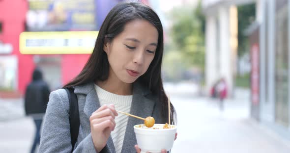 Woman eating fish ball, Hong Kong style snack