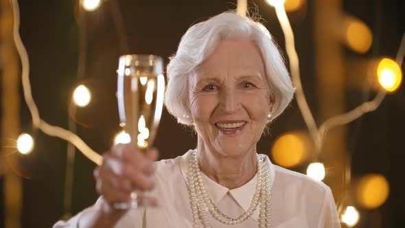 Happy Elderly Woman Raising Glass of Champagne