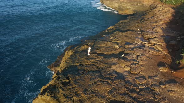 Epic adventure seeker drone shot of urban nomad traveler, hipster young millennial man stand on edge