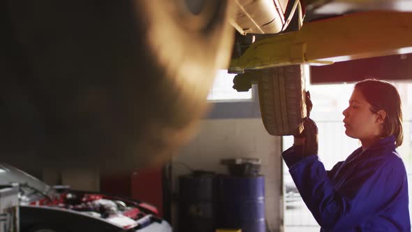 Female mechanic inspecting tire of the car at a car service station