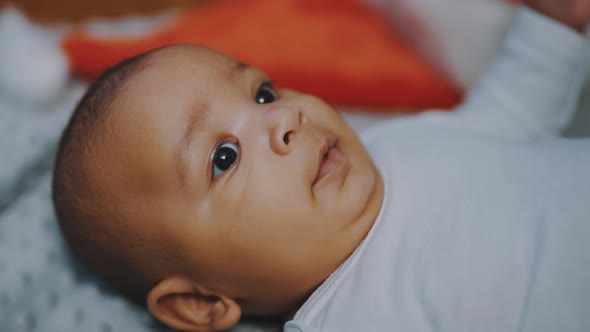 Portrait of Cute African American Black Baby with Funny Face Expression Relaxing on the Blanket