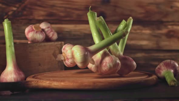 Super Slow Motion Garlic Falls on a Cutting Board on a Wooden Background