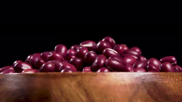 Red beans adzuki in wood bowl on black background. Turning