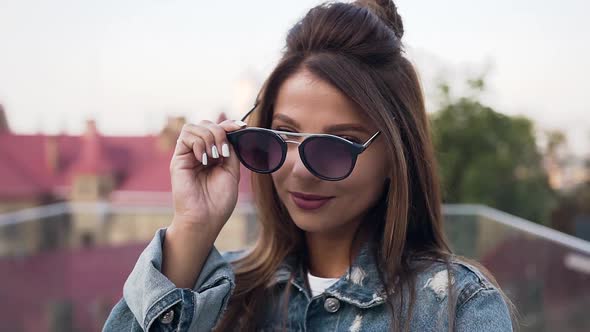 Young Woman with Long Hair Wearing Stylish Sunglasses and Posing on Camera