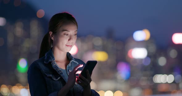 Woman use of mobile phone in city at night