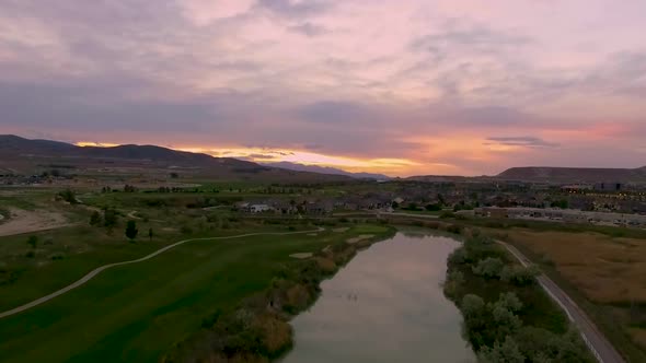 Flying backwards over a river and golf course with a stunning sunset in the distance and the colorfu