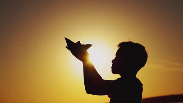 Paper boat is in the hands of a child. Beautiful summer sunset. Origami