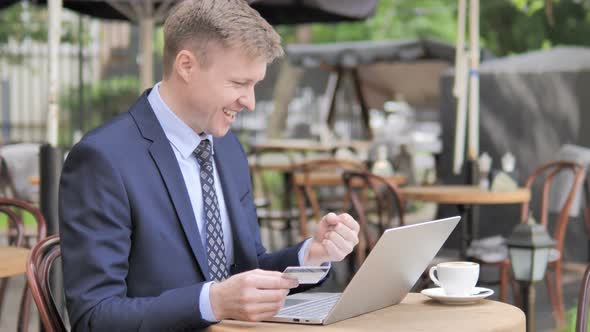 Successful Online Shopping by Businessman Sitting in Cafe Terrace