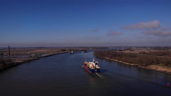 Freight ships in the water. Aerial view above the river. Drone goes up