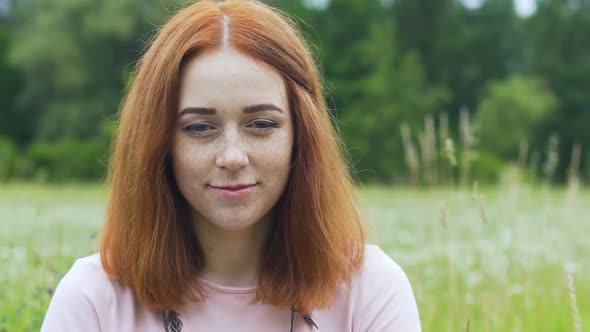 Red Haired Woman With Freckles Looks in Camera Outdoors in Field, Female Smile