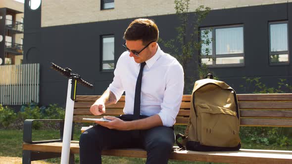 Businessman Writing To Notebook Sitting on Bench