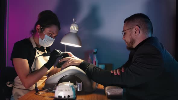 A Business Man Having His Nails Done in the Beauty Salon and Talking with His Woman Master