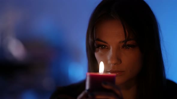 Closeup Portrait of a Darkhaired Woman Sitting and Holding an Aromatic Relaxing Candle Gazing at It