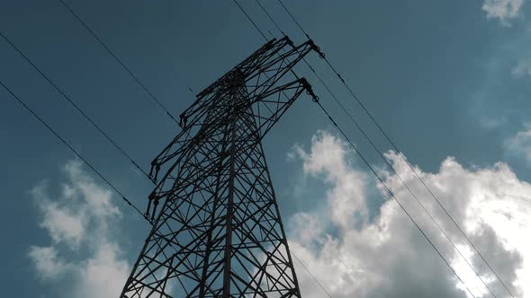 Bottom View of a High Voltage Power Pylons Against Blue Sky and Clouds