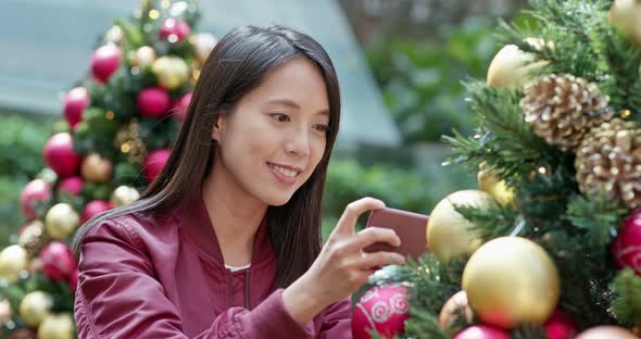 Woman take photo on cellphone with Christmas tree decoration 