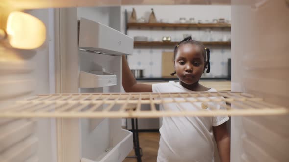 Hungry Poor Little African Girl Look for Food in Empty Fridge at Home