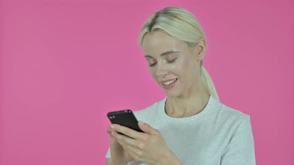 Young Woman Browsing Smartphone on Pink Background