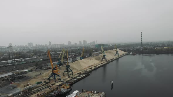 Aerial view of industrial city in smog and fog with construction cargo cranes working at docks