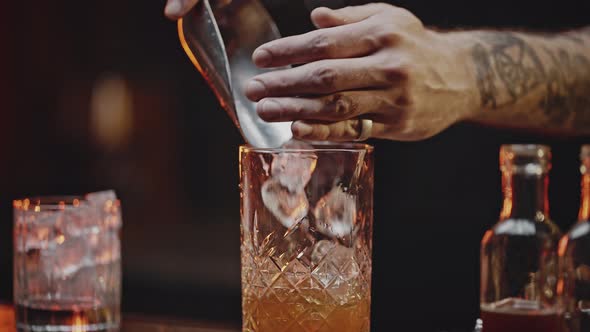 Professional Bartender Pours Ice Cubes Into Finished Drink